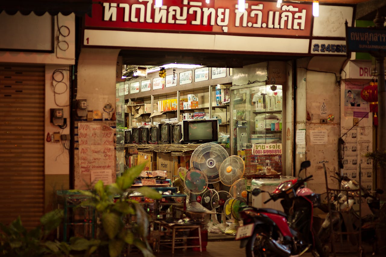A well-lit vintage electronics store with retro TVs and fans on display, viewed from the street.