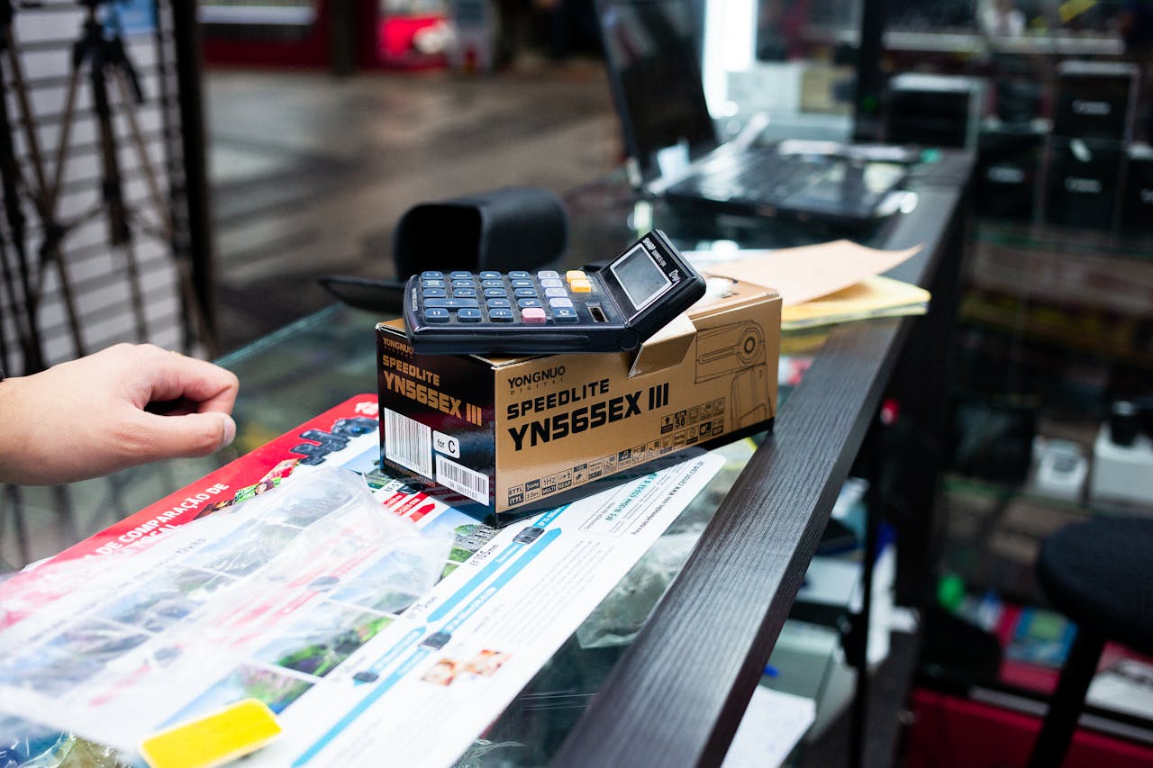 Close-up of a payment terminal and camera flash box on a store counter.